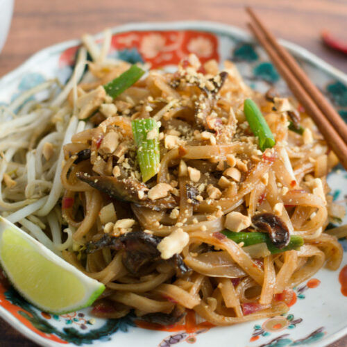 vegan pad thai with lime wedge and chopsticks on plate